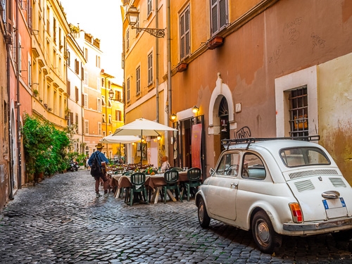 A street view of one of the narrow streets in Rome with shops and cafes on them 