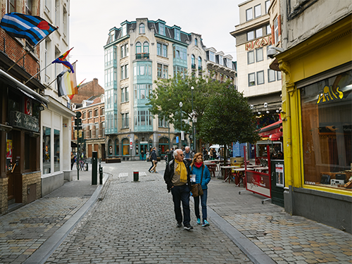 Two people walk down the street in Brussels, browsing the shop windows 