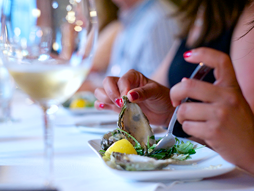 An up close picture of someone eating an oyster in a nice restaurant 