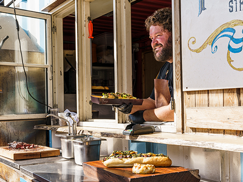  Man serves filled baguettes from an open hatch in Copenhagen, Denmark 