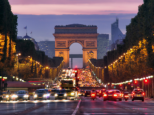 The Arc de Triomphe in Paris pictured at night time with evening traffic moving in both directions. Sigurboginn að kvöldlagi