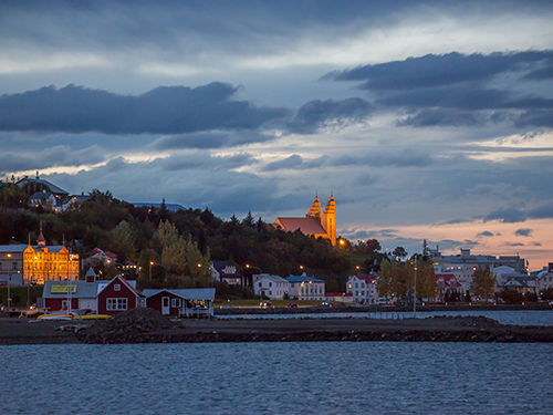 Akureyri by oplyst i skumringslys med kirken synlig 