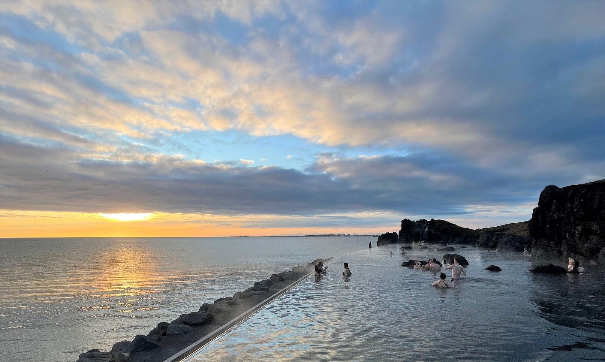 Swimmers at sunset in the infinity-edge pool of the Sky Lagoon