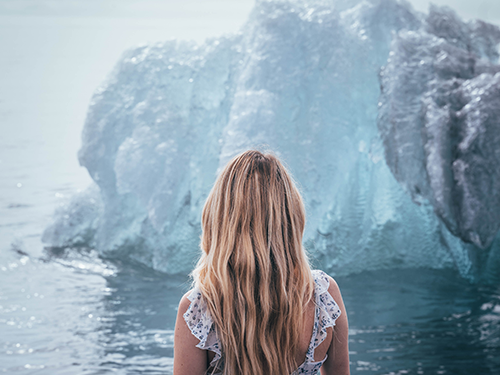 A blonde haired woman pictured looking out over Jökulsarlon Glacier Lagoon in Iceland 
