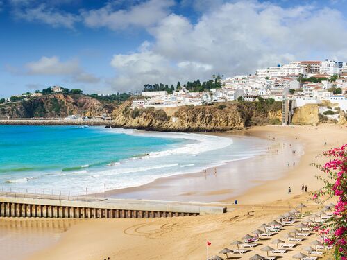 white sand beaches on the coast of Portugal with the town of Faro in the background