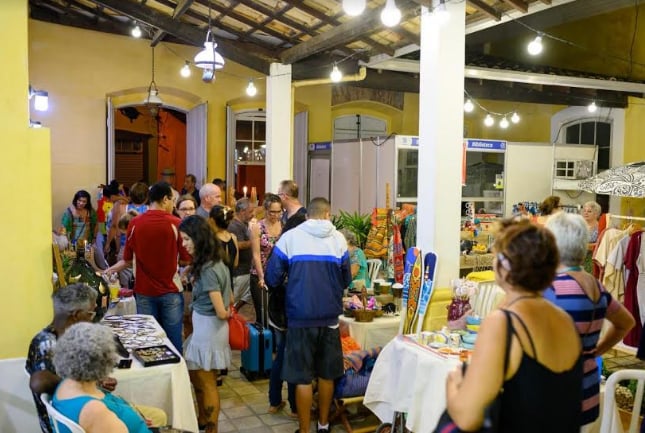 Feira de artesanato em São Sebastião, com barracas, luzes e movimento. Organize sua viagem com pontos na Livelo.
