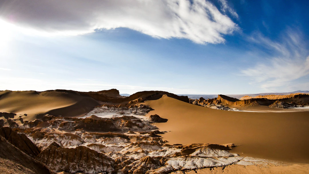 Dunas e formações rochosas no Deserto do Atacama sob céu azul. Planeje sua viagem com pontos na Livelo