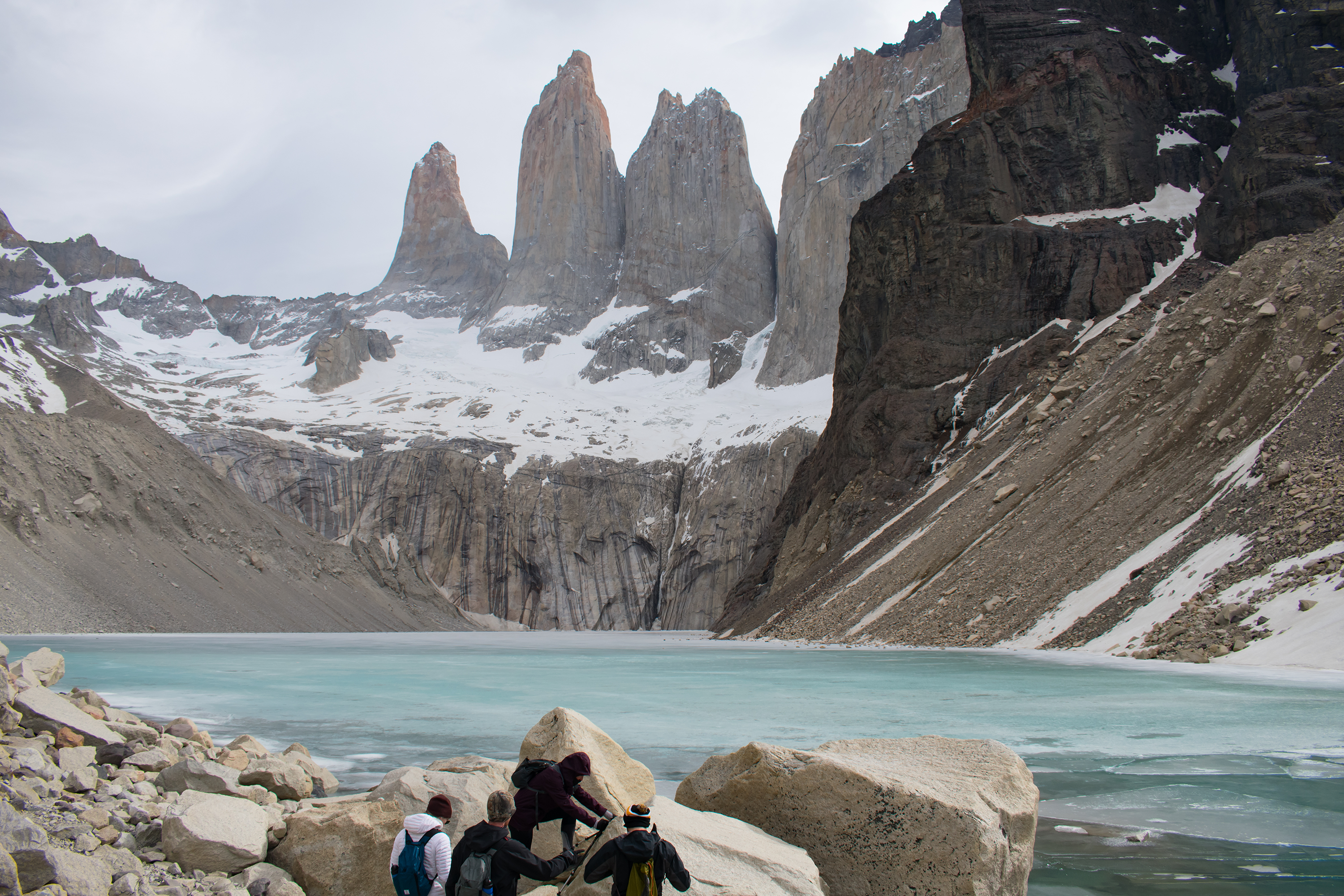 Vista do lago e das montanhas em Torres del Paine, Chile, com as torres encobertas por névoa e rochas nas margens. Planeje com pontos Livelo.