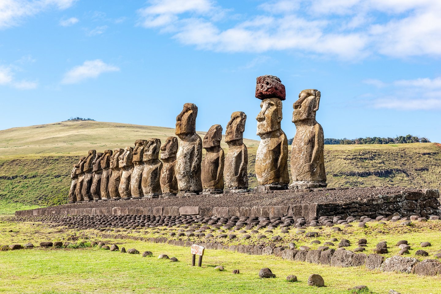 Ahu Tongariki na Ilha de Páscoa, Chile, com fileira de moais em pedra sobre plataforma e colinas ao fundo. Planeje com pontos Livelo.