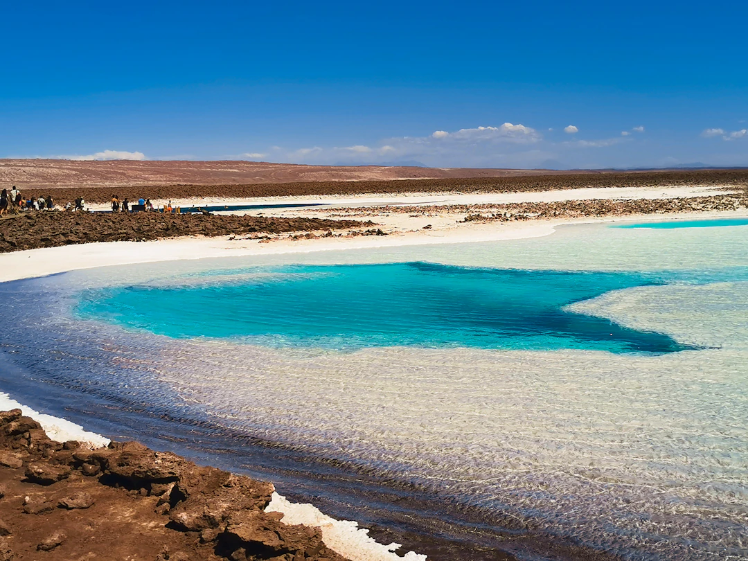 Lagoa de tom turquesa em paisagem salineira no Atacama, céu aberto e horizonte amplo. Planeje com pontos na Livelo.