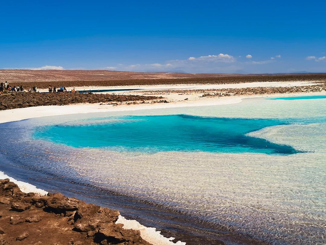 Lagoa de tom turquesa em paisagem salineira no Atacama, céu aberto e horizonte amplo. Planeje com pontos na Livelo.
