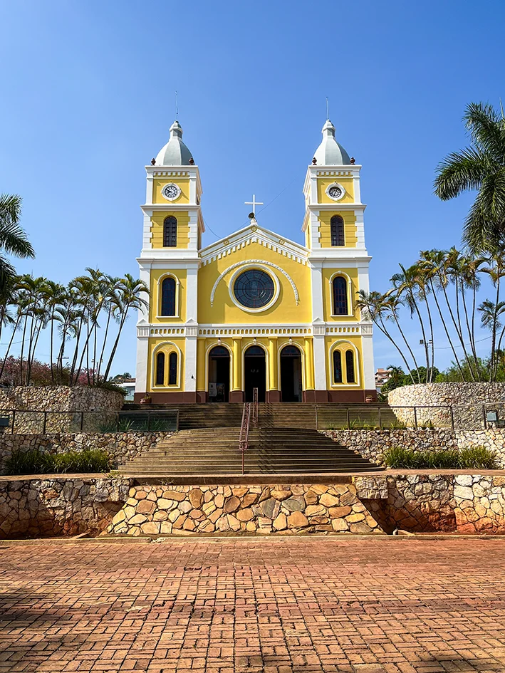 Igreja Matriz de São Sebastião em Capitólio - MG, fachada amarela com duas torres sob céu azul. Use seus pontos Livelo para viajar.