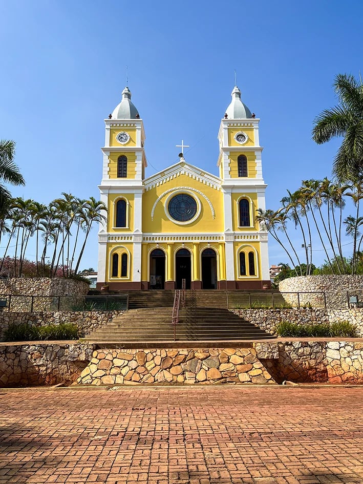 Igreja Matriz de São Sebastião em Capitólio - MG, fachada amarela com duas torres sob céu azul. Use seus pontos Livelo para viajar.