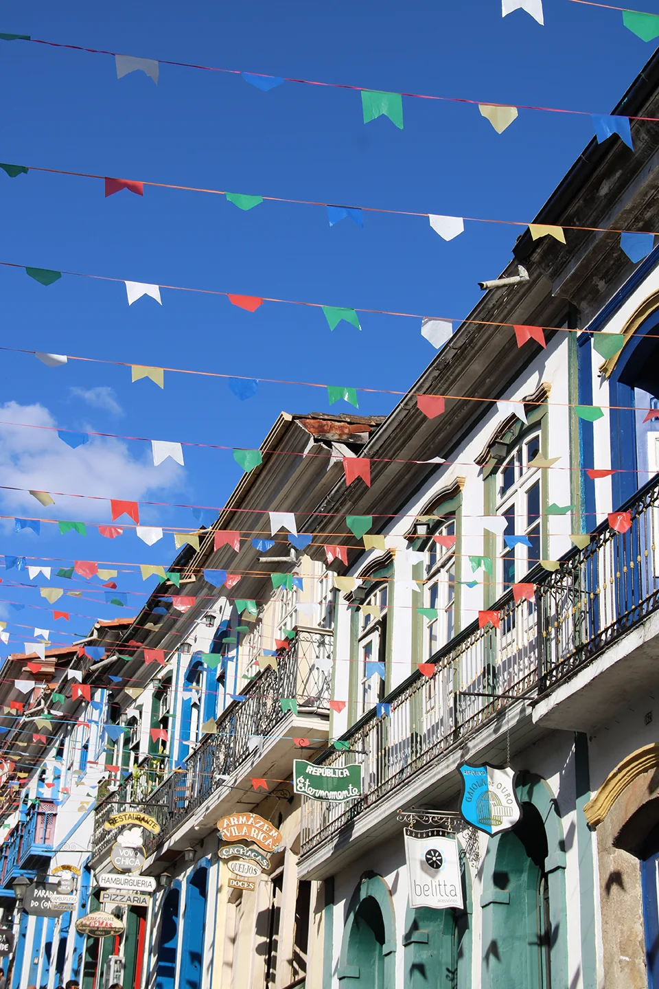 Rua com casarões e bandeirinhas coloridas no alto, clima de festa junina em Capitólio - MG. Planeje sua viagem com pontos Livelo.