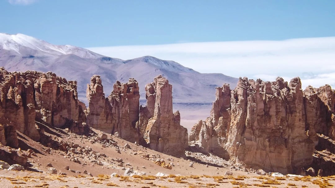 Formações rochosas no Atacama com montanhas ao fundo e luz intensa do deserto. Programe com pontos na Livelo.