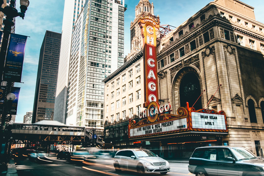 Fachada do Chicago Theatre no centro da cidade, com letreiro histórico, prédios altos e carros em movimento na rua. Conheça os clássicos de Chicago com pontos Livelo.Fachada do Chicago Theatre no centro da cidade, com letreiro histórico, prédios altos e carros em movimento na rua. Conheça os clássicos de Chicago com pontos Livelo.