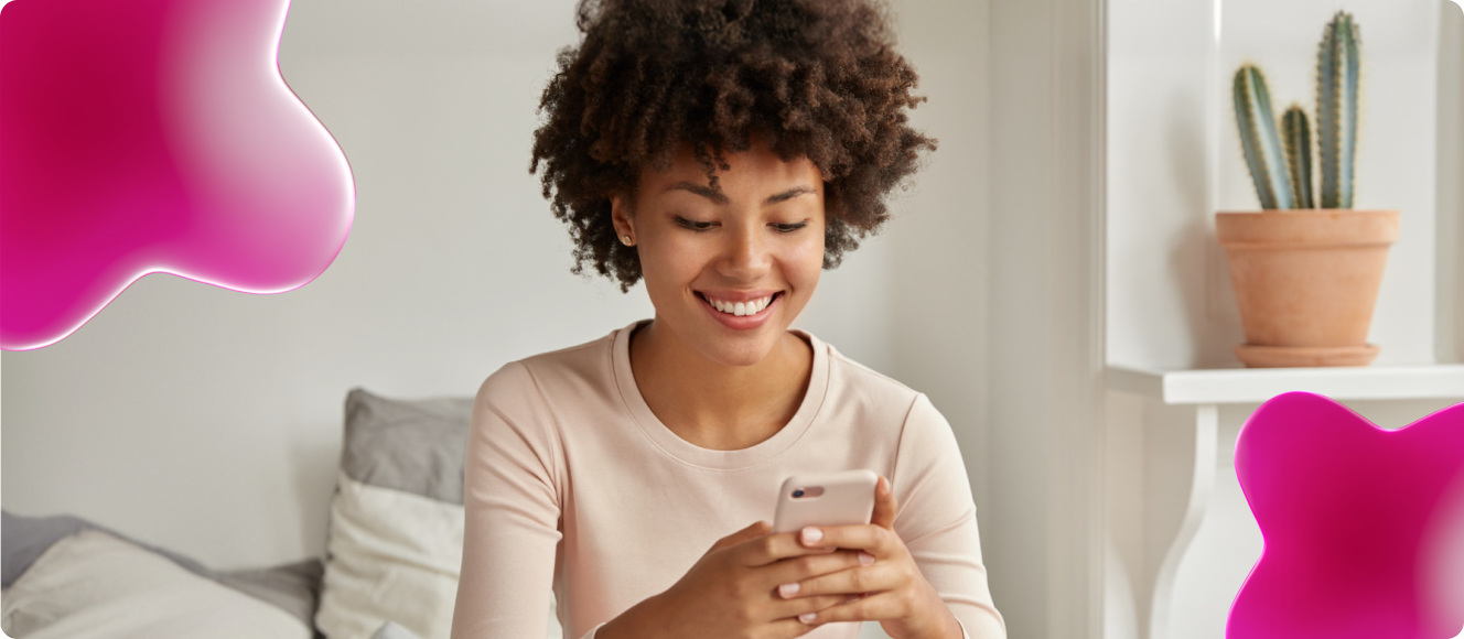 Uma mulher sorridente sentada no sofá utilizando seu celular.