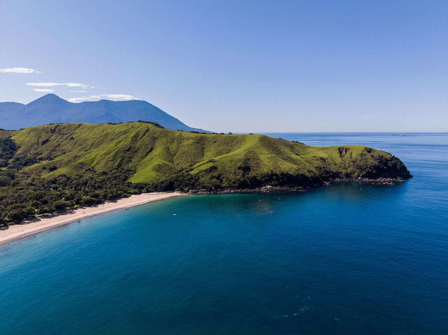 Panorama aéreo de São Sebastião com costa recortada, morros e mar cristalino. Organize com pontos na Livelo.
