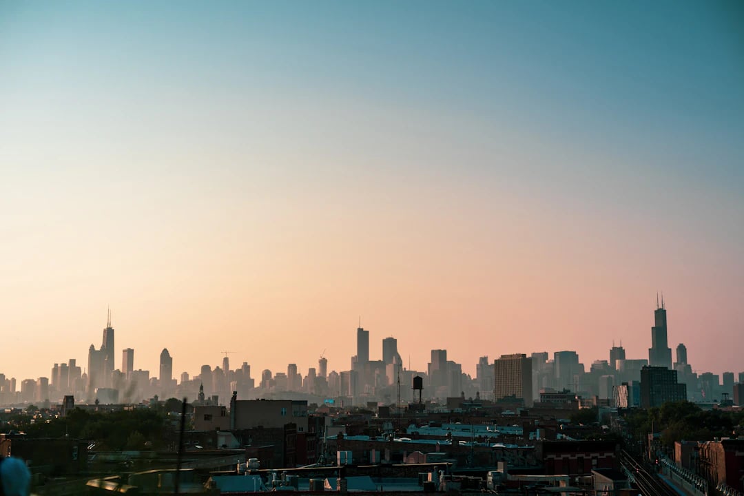 Horizonte de Chicago ao pôr do sol, com silhueta dos arranha-céus vista de longe sob céu em tons suaves. Descubra Chicago com pontos Livelo.
