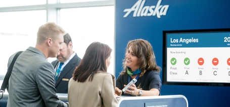 A picture of passengers and Gate Agent in-front of a Boarding Pass GID Screen. 