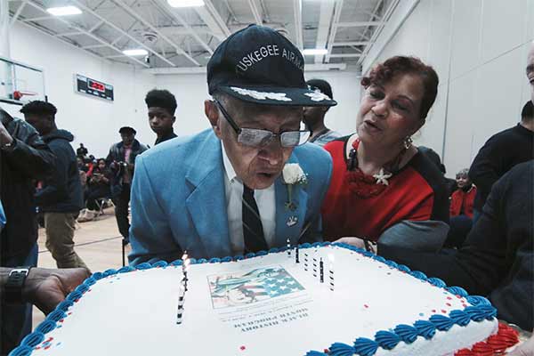 A veteran blowing out candles on a cake.