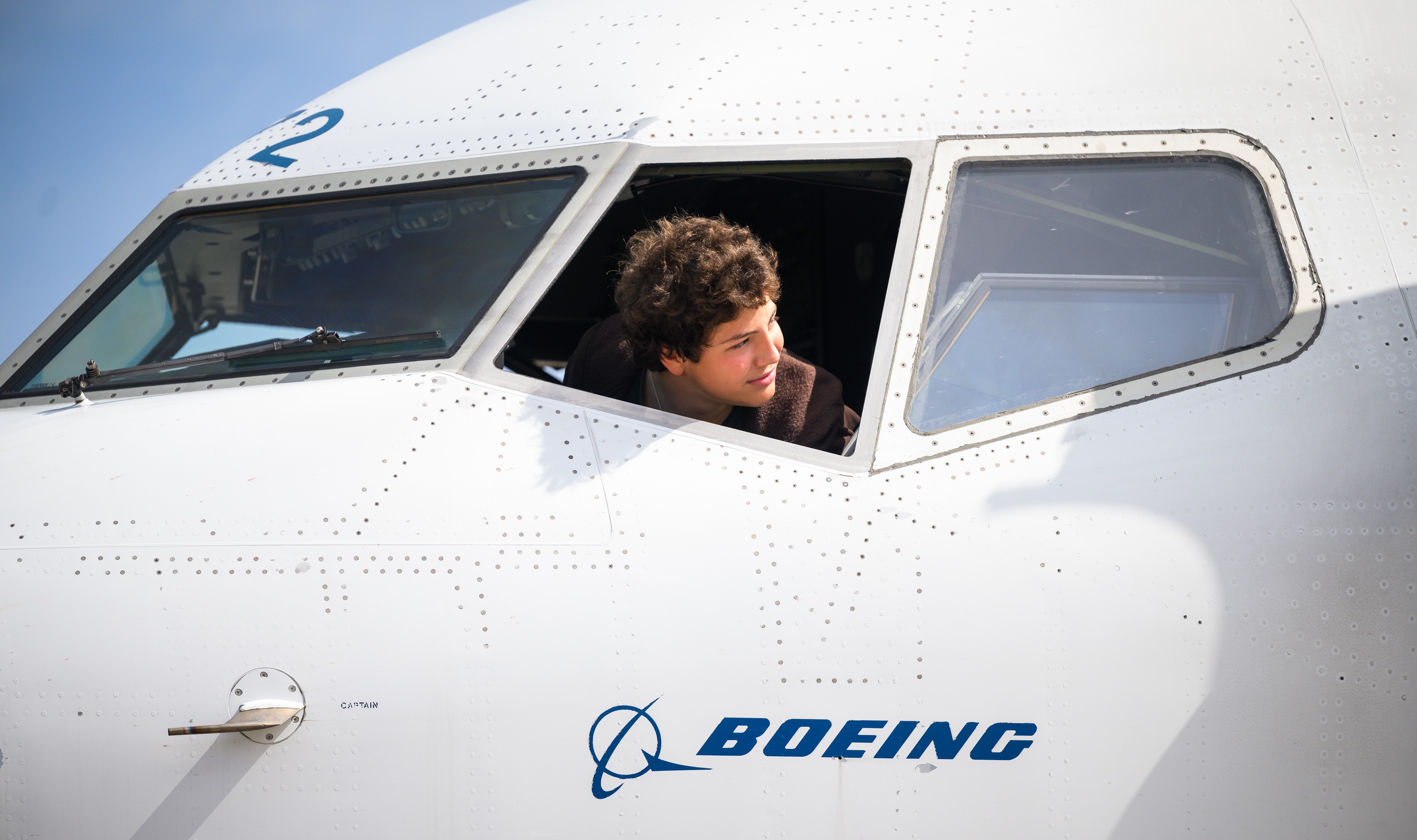 Un adolescente mirando por la ventanilla de la cabina de pilotos.