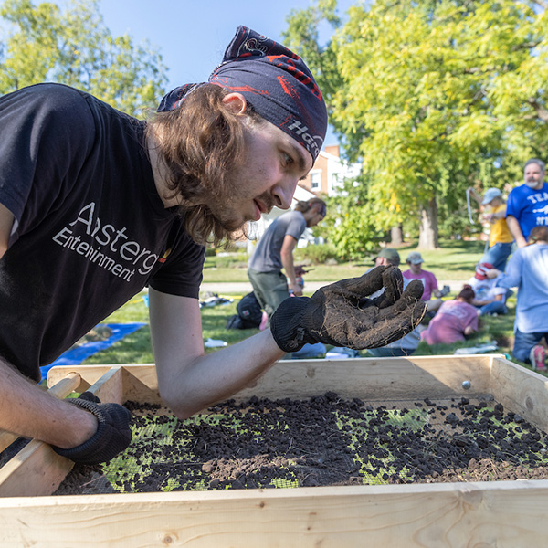 An archaeology student inspects an item found in the shaker screen.