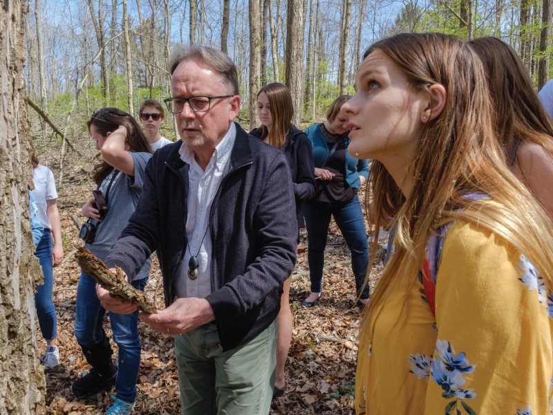 Nicholas Money working with a group of students in the woods.