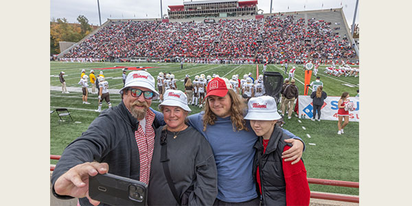 A Miami family huddles close together for a photo during the RedHawks football game at Yager Stadium