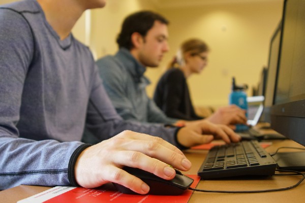three student sitting at row of computers with a closeup view of keyboards
