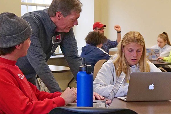 professor working with two students at desk