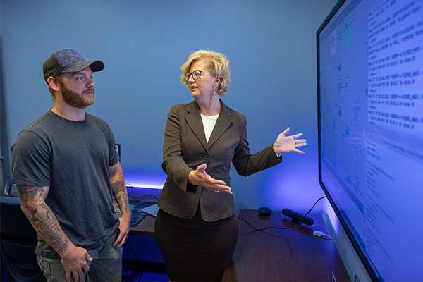 A faculty member showing a student a screen of information in the classroom.