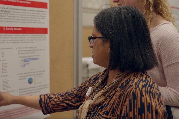 Director Joyce Fernandez listening to a student presentation at the Undergraduate Research Forum.
