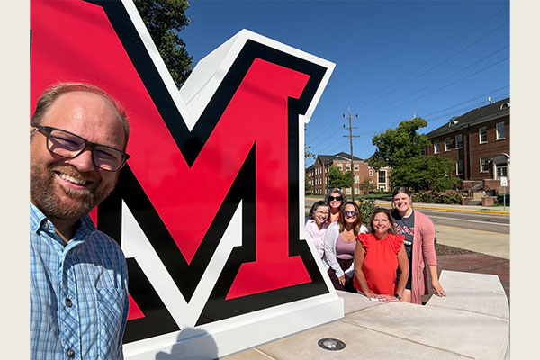A Miami family takes a selfie in front of the large Miami M on the Oxford campus.