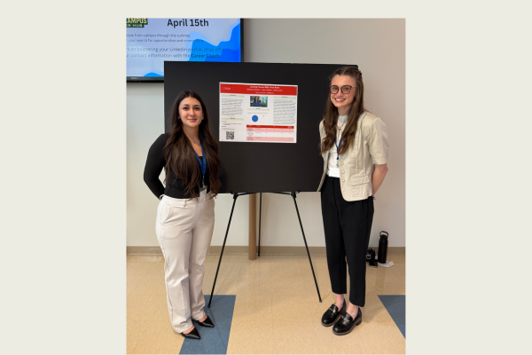 Taylor Whitton and Madison Roberts standing in front of their poster research at the AURCO conference.