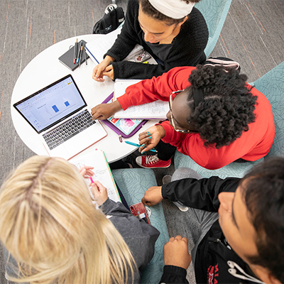 A group of students working together at a table on their computers.