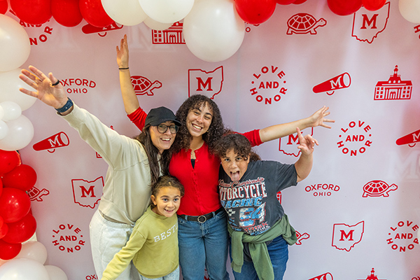 a family posing in front of a background at family weekend