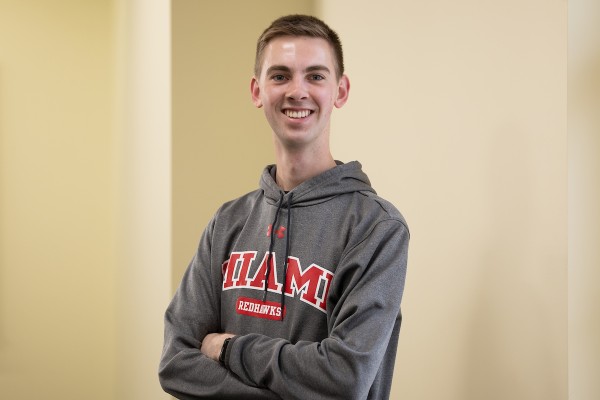 Levi Grimm standing in front of a wall wearing a Miami sweatshirt