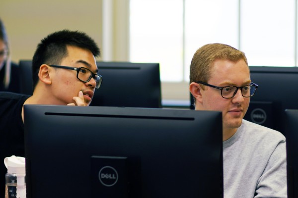 two students looking at computer monitors during class session