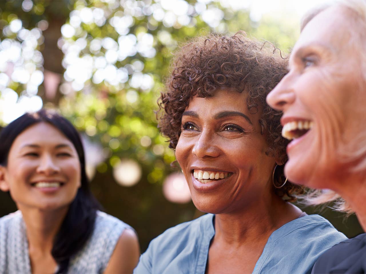 Three women joyfully laughing together at Women’s Wellness Day event.