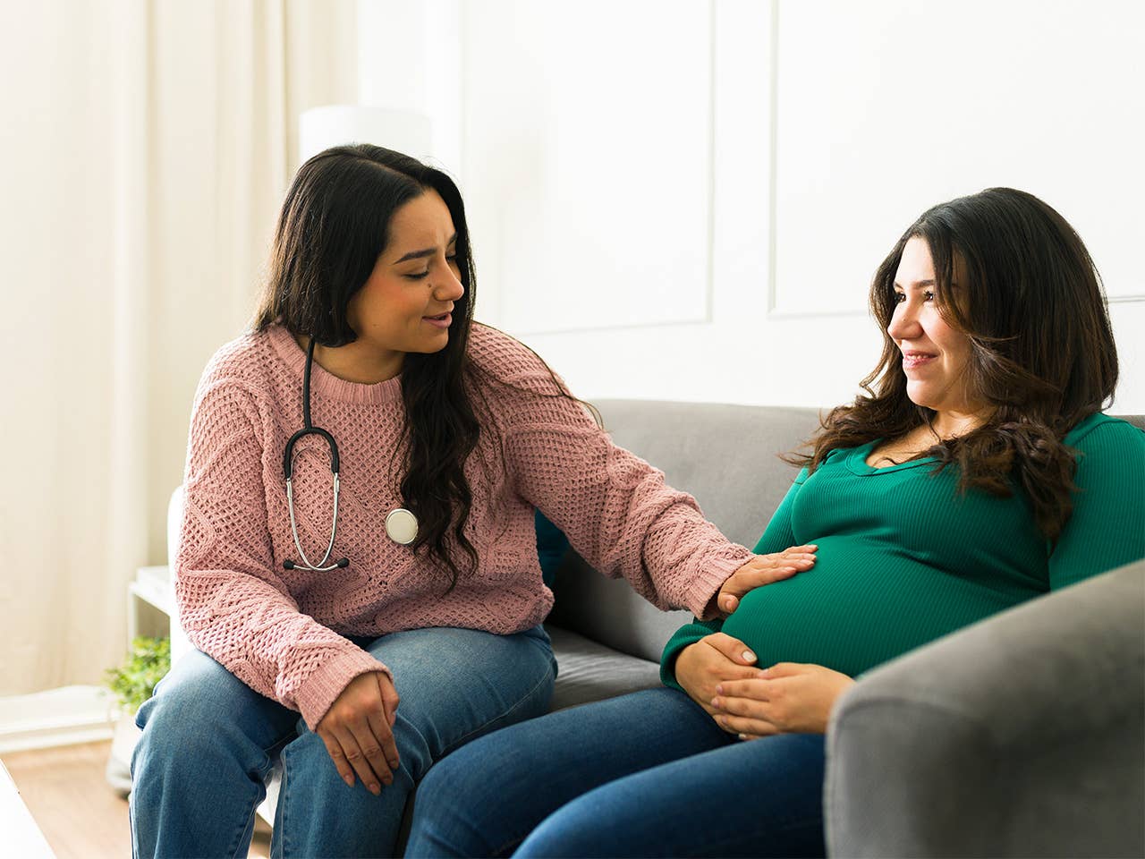 Corewell Health midwife places a hand on the belly of a patient she sits next to