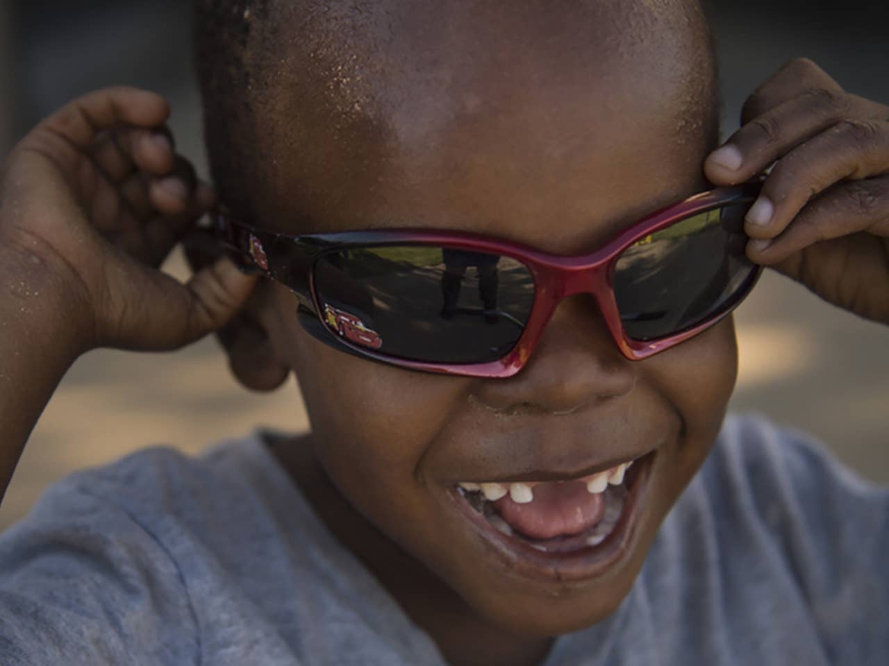 Smiling young Black boy wearing red sunglasses