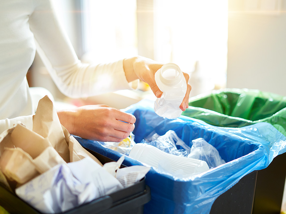 A woman discards trash into a trash can, promoting cleanliness and proper waste disposal.