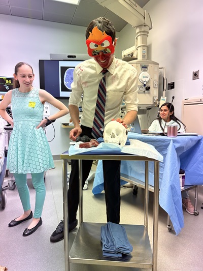 A man wearing a clown mask is slicing a cake, creating a whimsical and festive atmosphere.