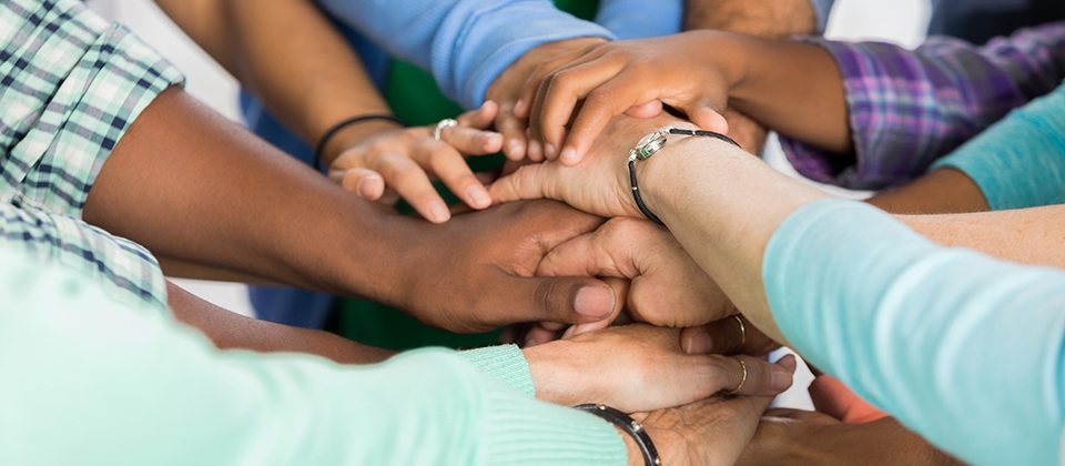 A diverse group of people standing in a circle, holding hands together in a show of unity and support.
