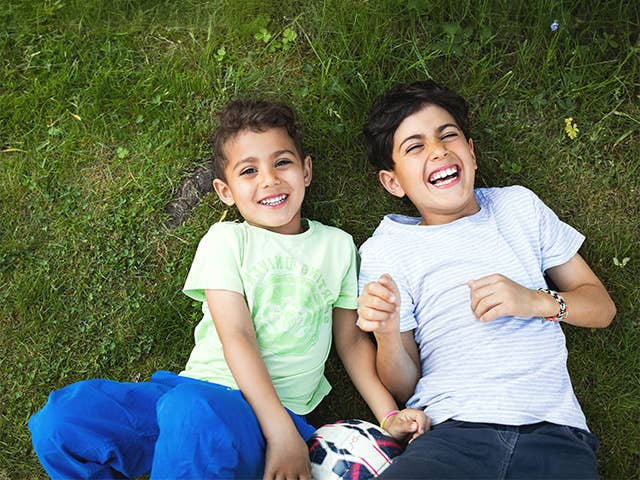Smiling boy and girl lay next to one another in the grass
