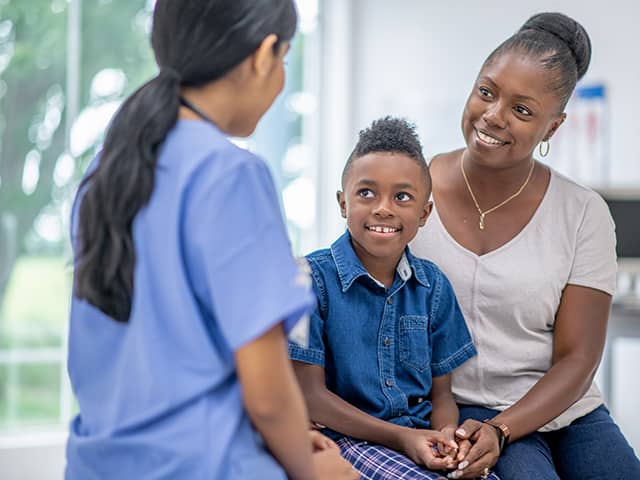 A mother and child sitting together engaged in conversation with a physician.