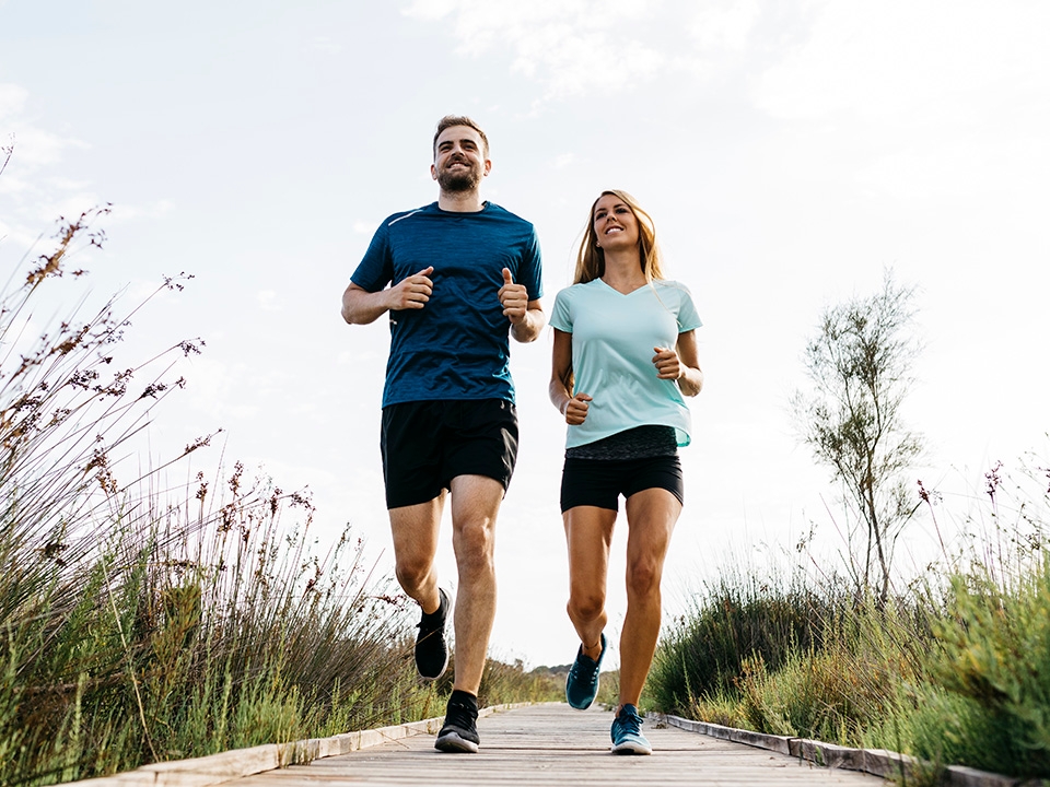 Middle aged man and woman walk together on a pathway through wild grasses in the evening