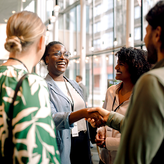 A group of professionals shaking hands in an office setting, symbolizing collaboration and agreement.