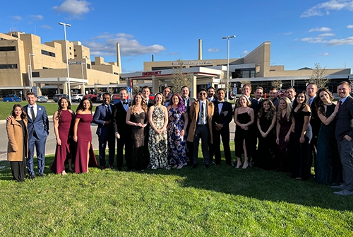 A group of individuals in formal attire gathered in front of a building, showcasing a moment from a resident outing.